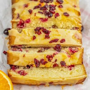 Slices of orange cranberry bread topped with orange glaze and chopped dried cranberries.