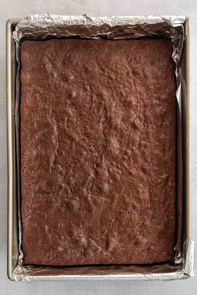 A freshly baked rectangular buckeye brownie in a foil-lined baking tray.