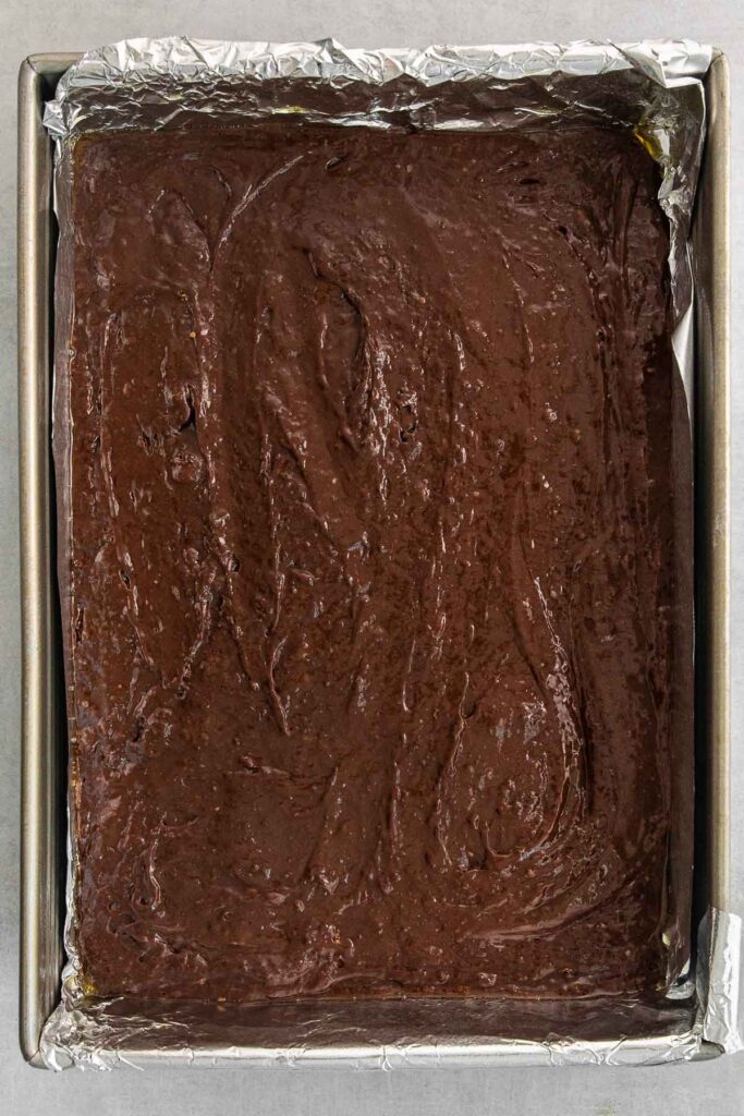 Chocolate layer of the brownie mix spread n a rectangular baking sheet.