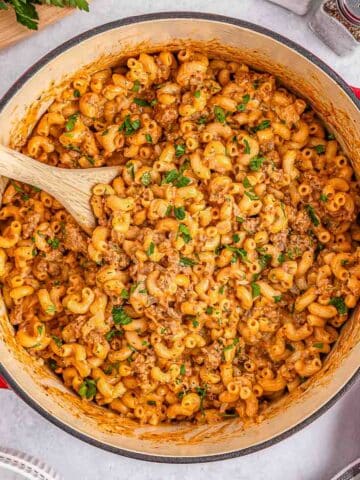 A large pot full of homemade hamburger helper ready to be served with a wooden spoon inserted.