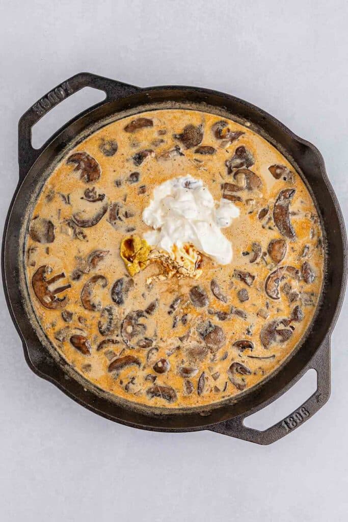 Cast iron skillet of mushroom and sauce, topped with a dollop of sour cream.