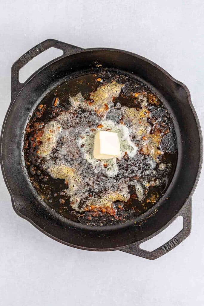 A black cast iron skillet with melted butter.