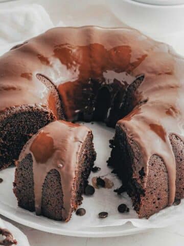 Chocolate Sweet Potato Cake with a chocolate frosting, partially sliced, placed on a parchment-lined plate.